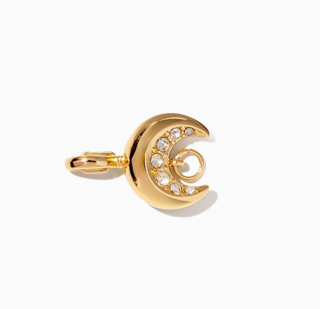 A gold crescent moon charm with a row of clear rhinestones, shown on a clean white background.