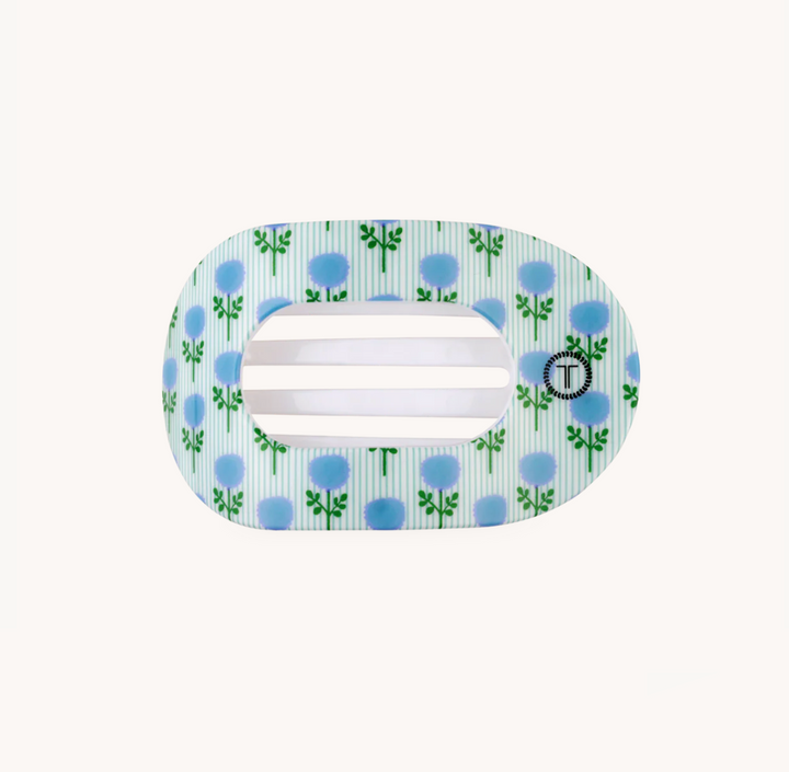 A light blue and white striped hair clip with a blue rose pattern and a small black circular logo featuring a white &