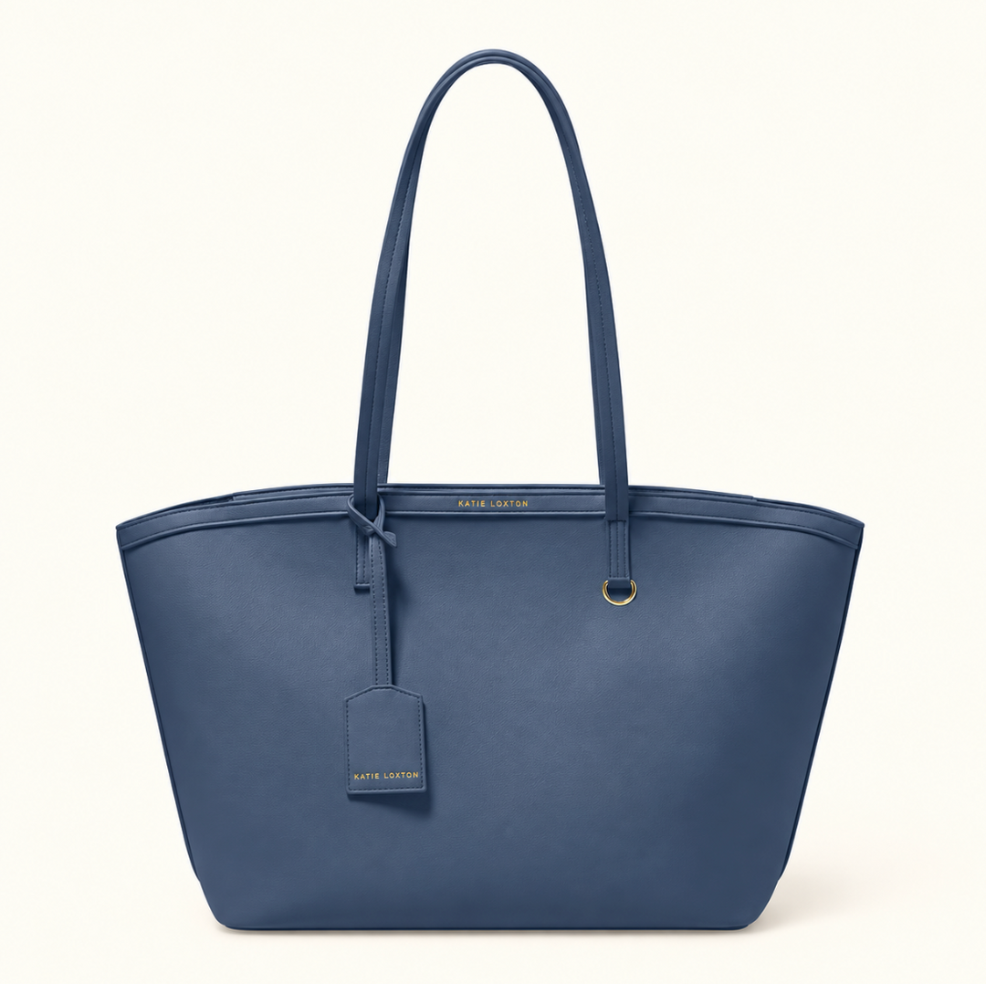 Katie Loxton Travel Tote in Navy featuring soft vegan leather, long shoulder straps, gold-tone hardware, and attached luggage tag.
