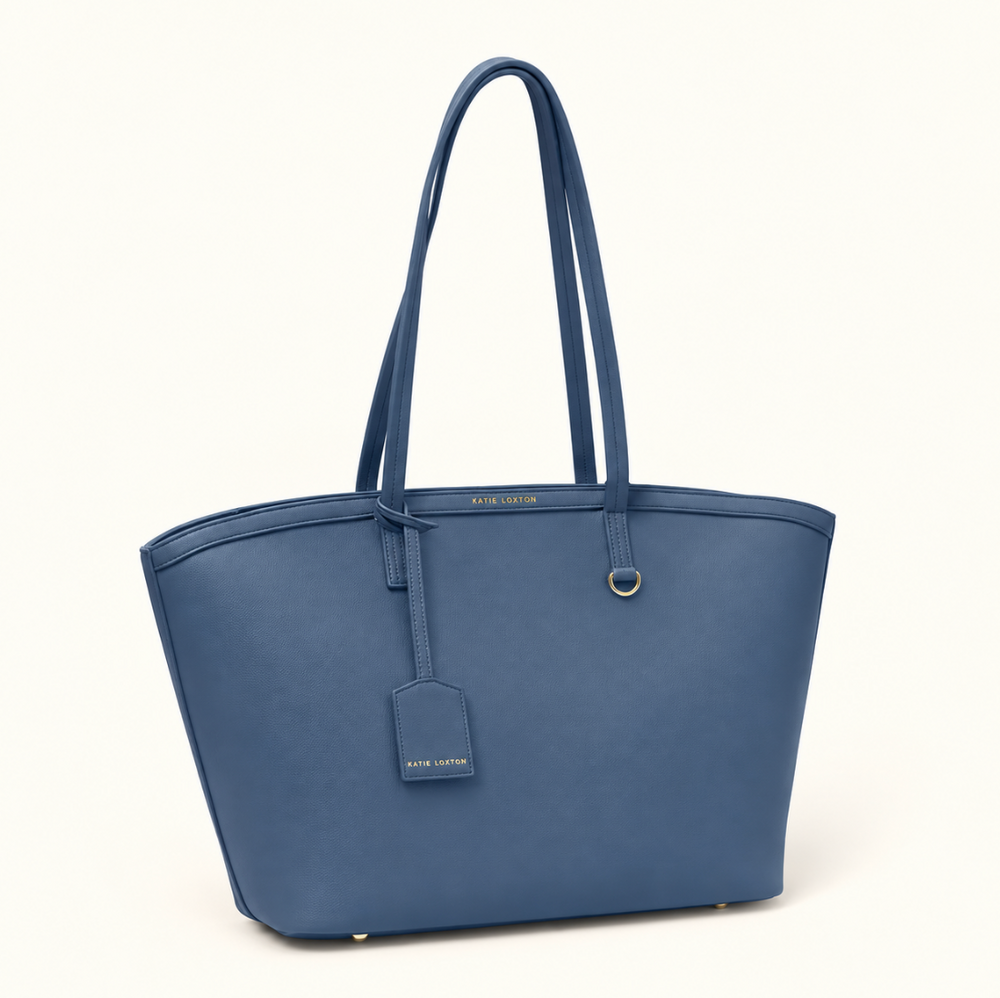 Angled front view of Katie Loxton Travel Tote in Navy with spacious structured design, long shoulder handles, luggage tag, and gold-tone accents.