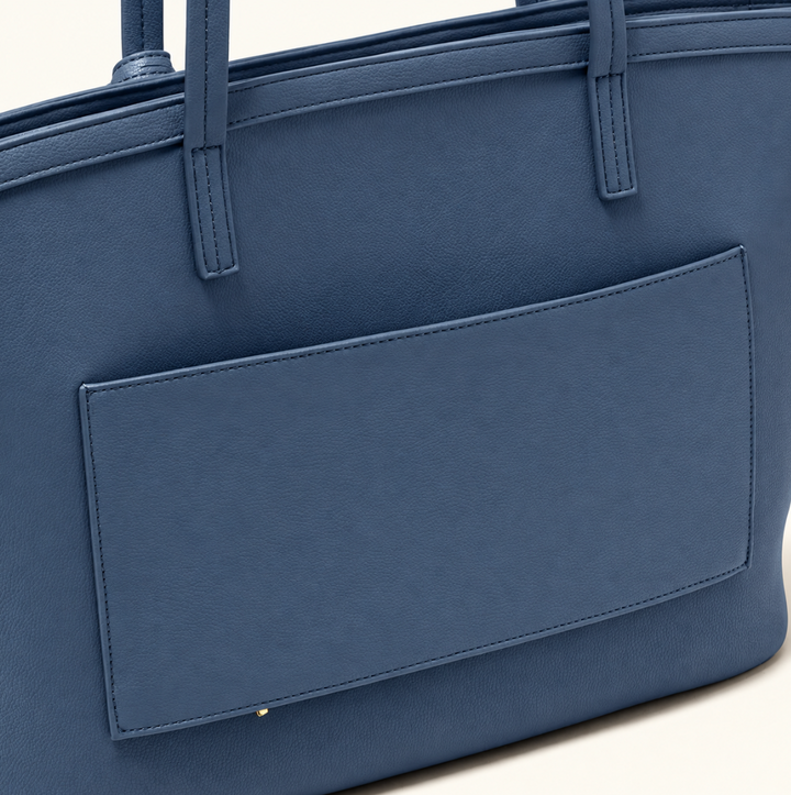 Close-up back view of the Katie Loxton Travel Tote in Navy featuring soft vegan leather, structured stitching, long shoulder straps, and a large exterior slip pocket.