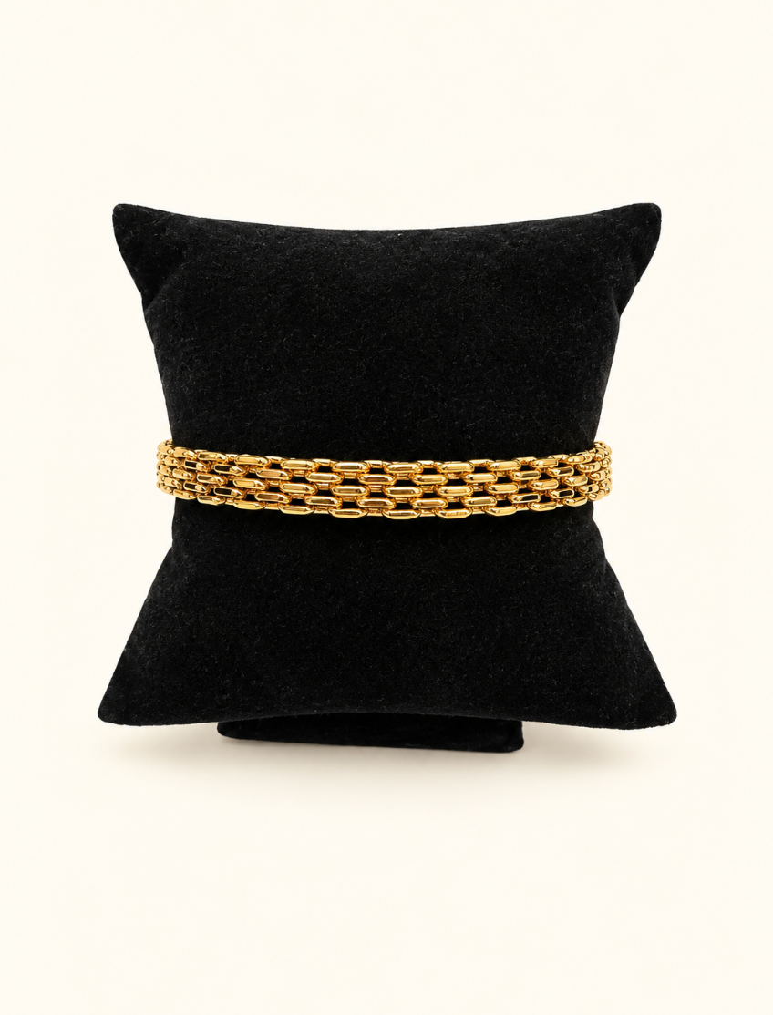 Katie Loxton Braid Chain Bracelet in gold displayed on black velvet jewelry pillow against a cream studio background