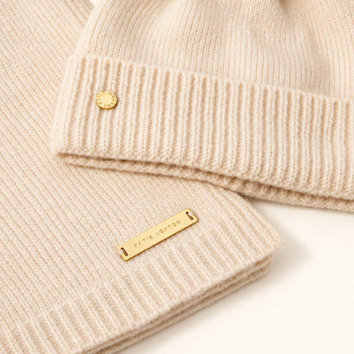Close-up of Katie Loxton Eggshell knitted hat and scarf showing soft knit texture and gold Katie Loxton logo hardware