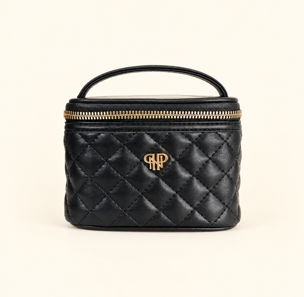 Black Timeless Quilted Getaway Jewelry Travel Case featuring diamond quilted vegan leather, gold zipper hardware, a top carrying handle, and gold logo on a cream studio background.
