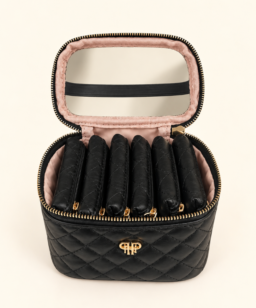 Open black quilted jewelry travel organizer displaying six removable zippered jewelry pouches, blush pink interior lining, and clear-view lid on a cream studio background.