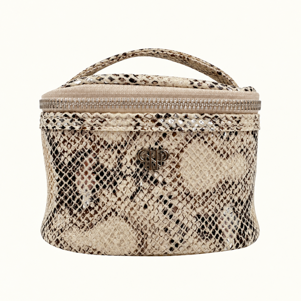 Safari Sands Getaway Jewelry Travel Case in cream python print with metallic accents, silver zipper, top handle, and logo on a cream studio background.