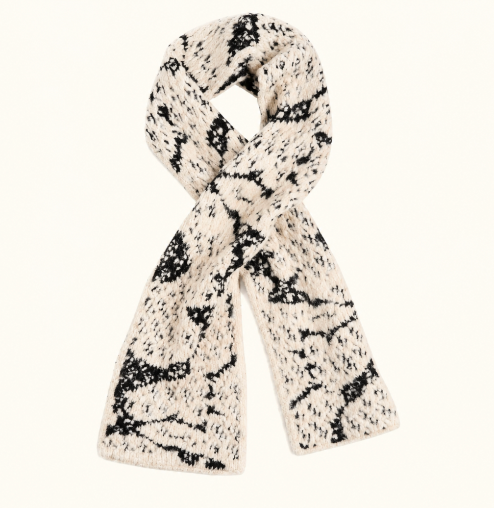 CoCo + Carmen Blizzard Season Scarf in black and cream featuring a soft, chunky textured knit with a snowflake-inspired pattern, styled in a loop on a cream studio background.