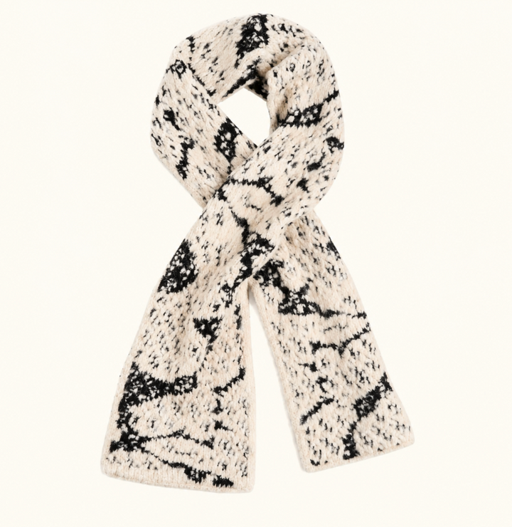 CoCo + Carmen Blizzard Season Scarf in black and cream featuring a soft, chunky textured knit with a snowflake-inspired pattern, styled in a loop on a cream studio background.