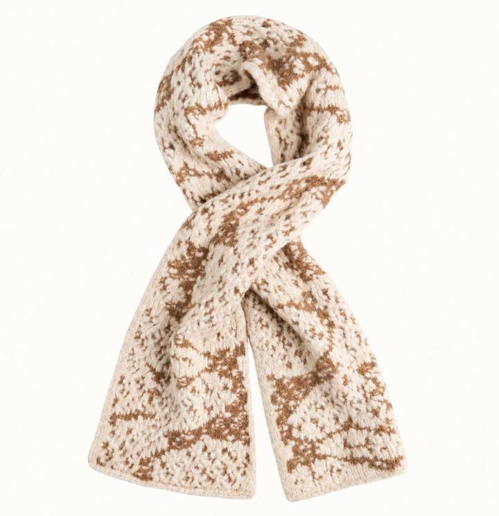 CoCo + Carmen Blizzard Season Scarf in beige and cream featuring a soft, chunky textured knit with a neutral winter-inspired pattern, styled in a loop on a cream studio background.