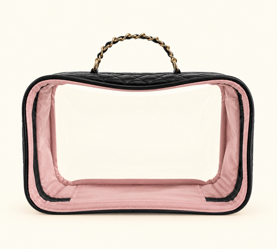 Black quilted clear cosmetic travel case featuring a transparent front, blush pink interior lining, zippered closure, and gold chain handle on a cream background.