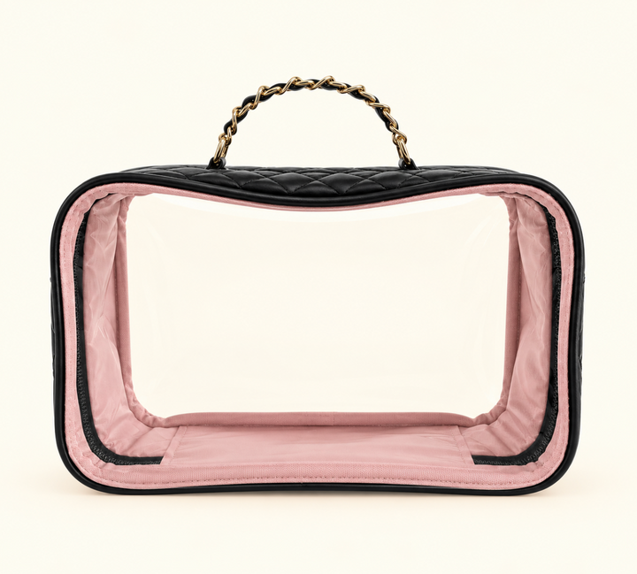 Black quilted clear cosmetic travel case featuring a transparent front, blush pink interior lining, zippered closure, and gold chain handle on a cream background.