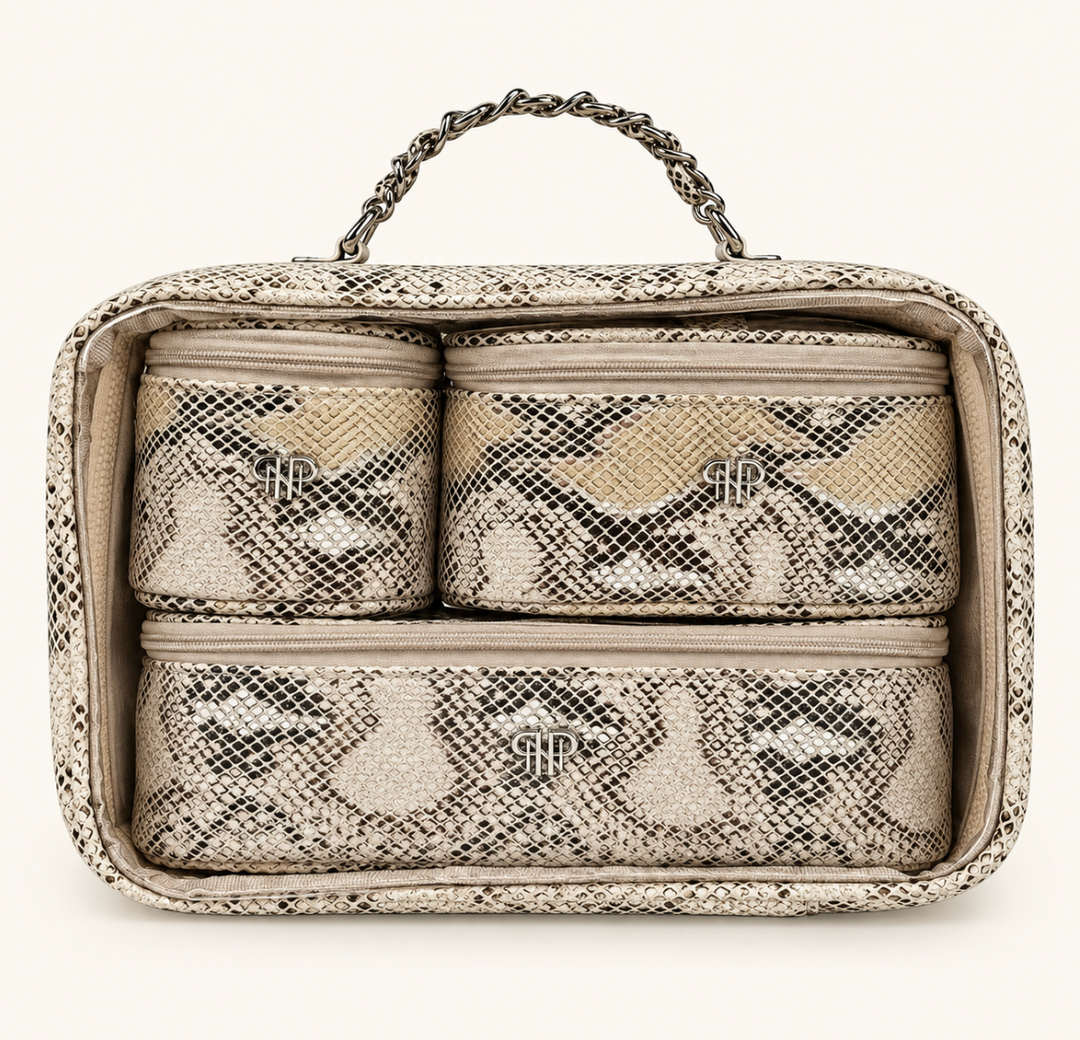 Snakeskin print makeup travel organizer set featuring three matching zippered cosmetic bags neatly packed inside a clear carrying case with silver chain handle.