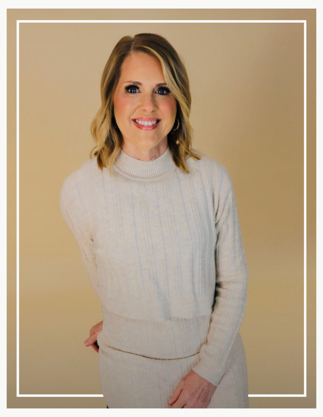 Woman wearing a light gray sweater against a beige background