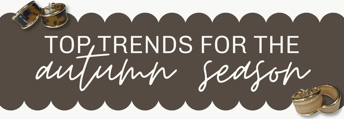 A promotional banner with the text 'TOP TRENDS FOR THE autumn season' in white lettering over a dark brown scalloped background, decorated with small fashion accessory illustrations in the corners | Square 1 Boutique | Brent, AL