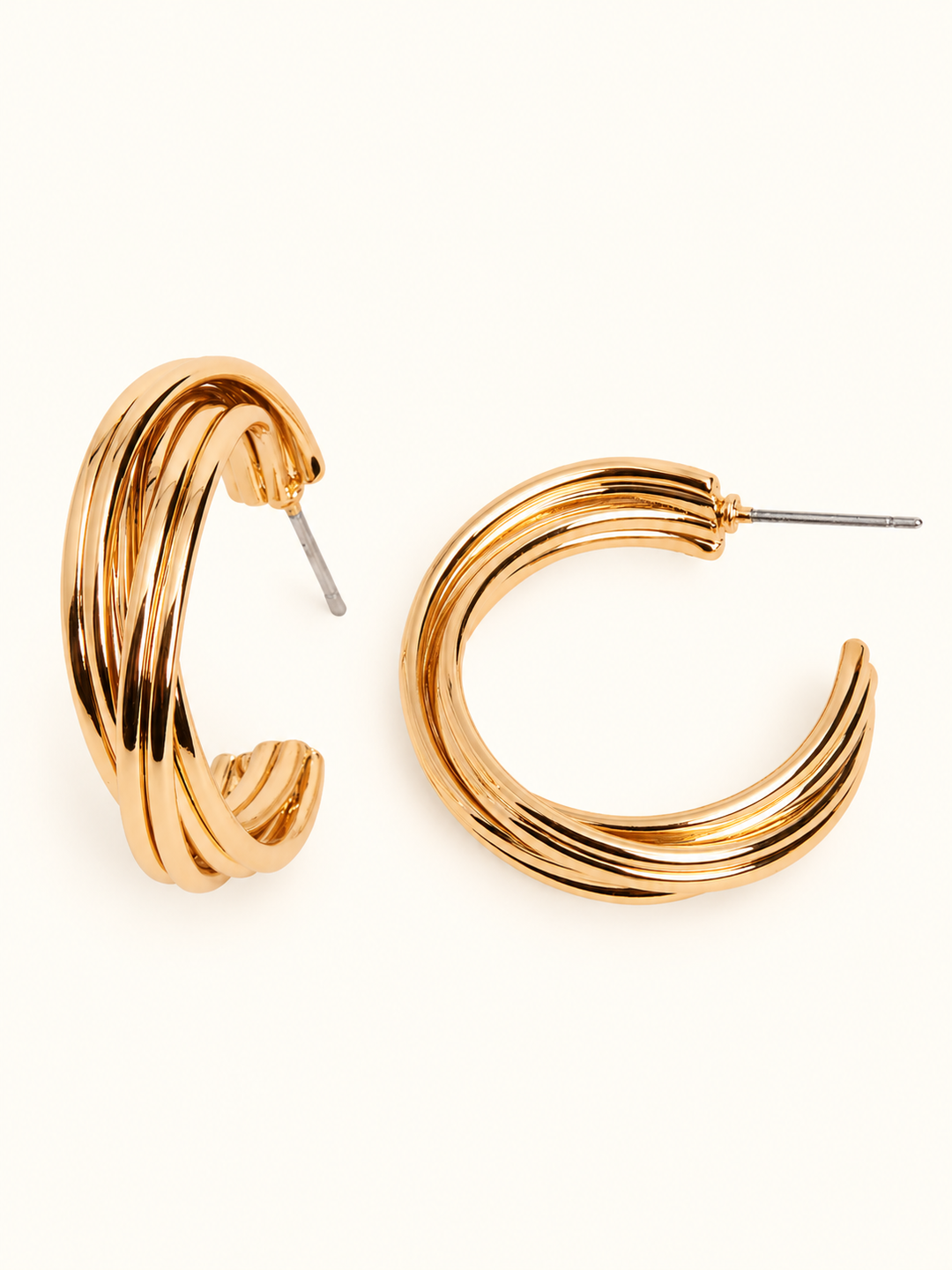 0.75-inch gold-tone layered hoop earrings featuring a chunky, multi-band curved design, polished finish, and post closures on a cream background.