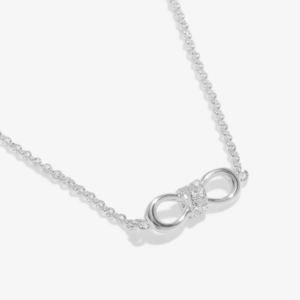 Silver infinity necklace with silver crystal accents in the center on a white background.