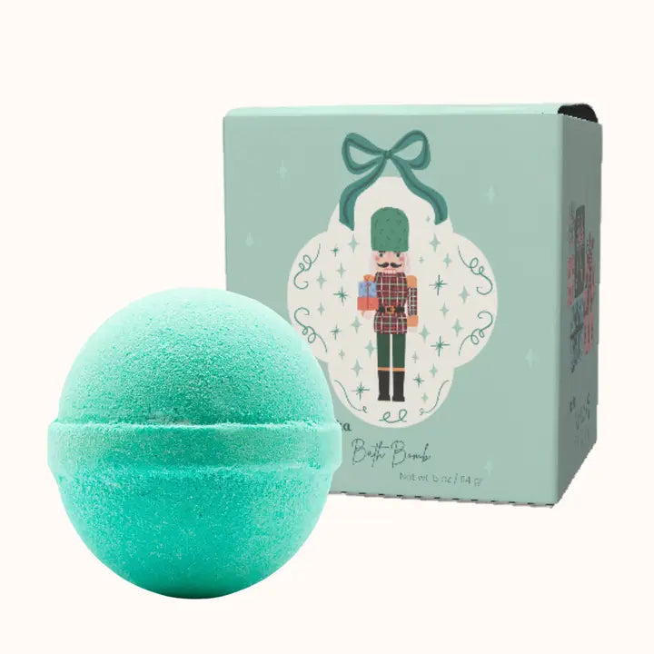 Turquoise bath bomb with a decorative box featuring a nutcracker design on a white background